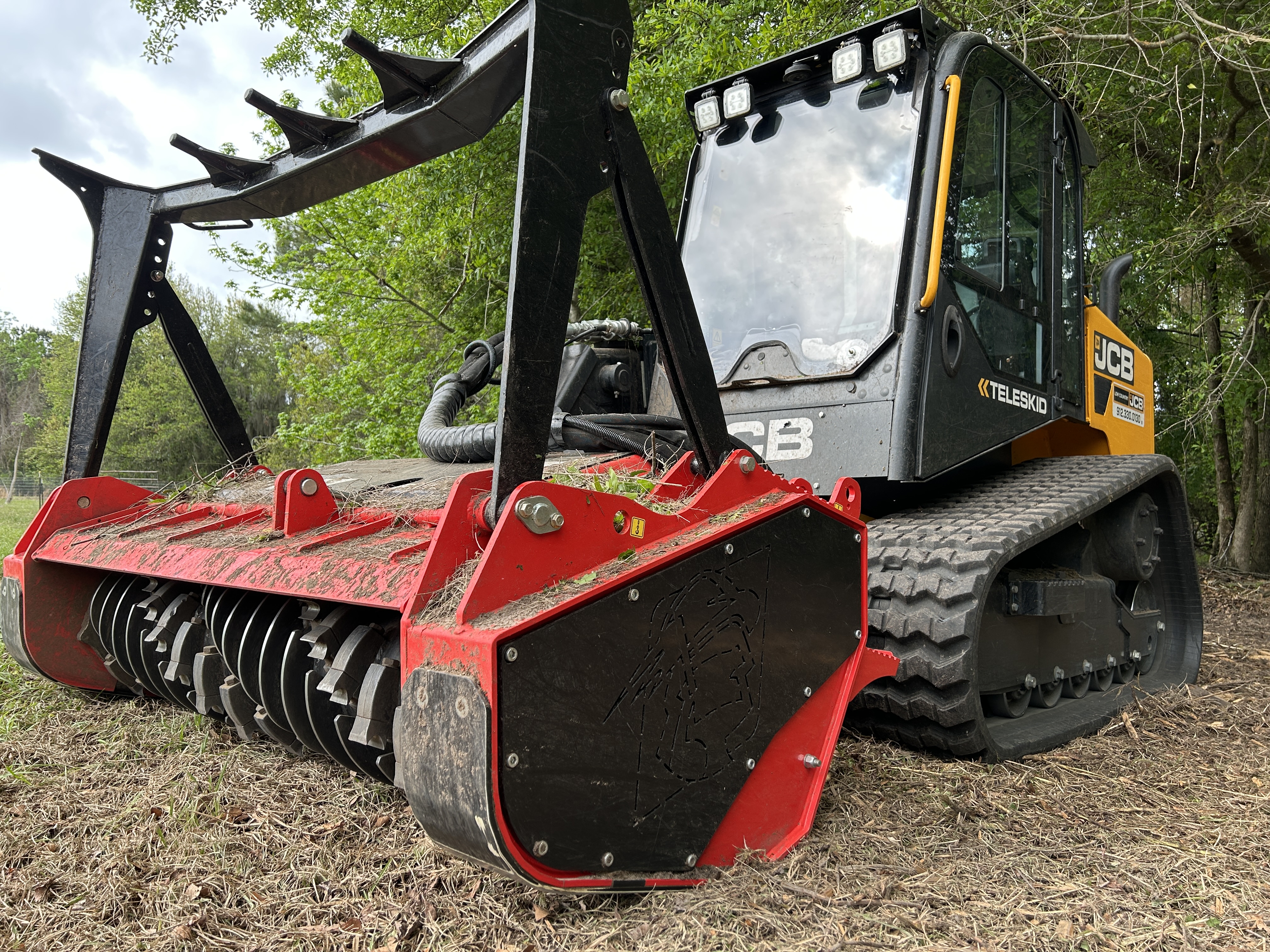 Close-up of JCB Teleskid with red forestry mulcher attachment